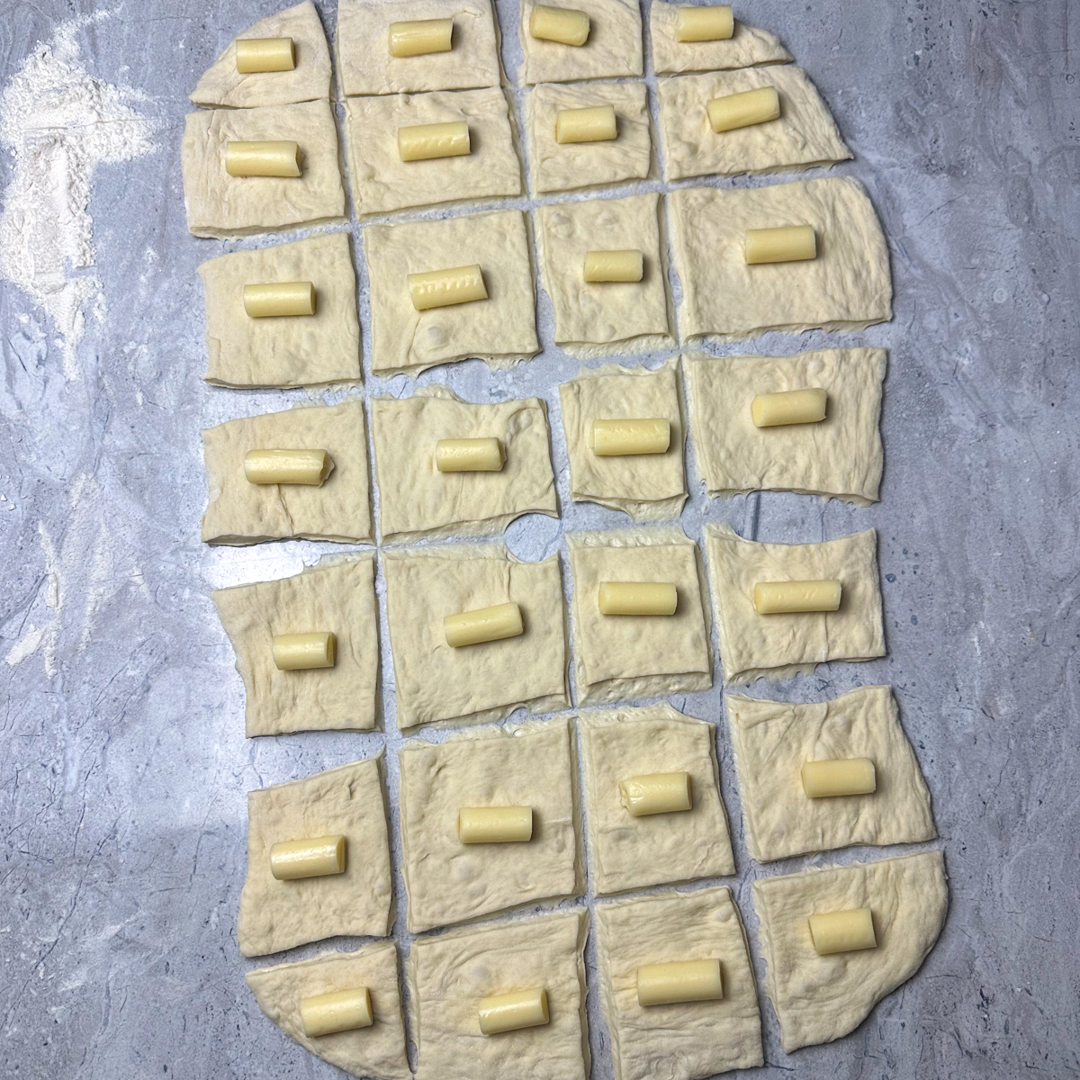 Cut the pizza dough into squares & add the mozzarella sticks!