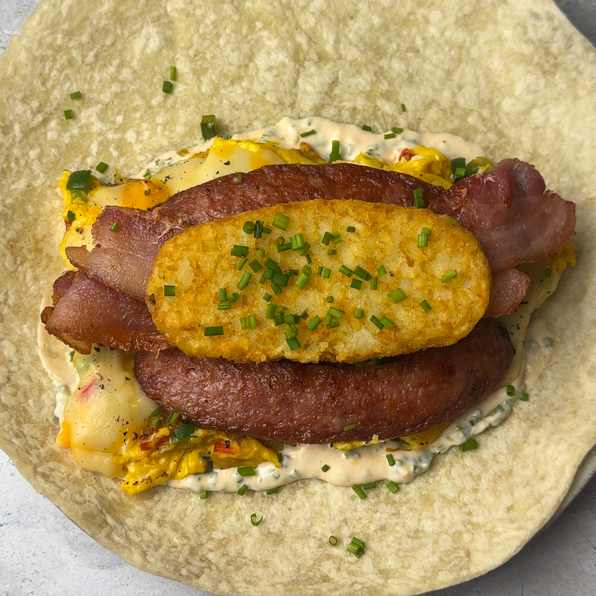 Assemble the burrito with the mayo, cheesy eggs, meat & hash brown!