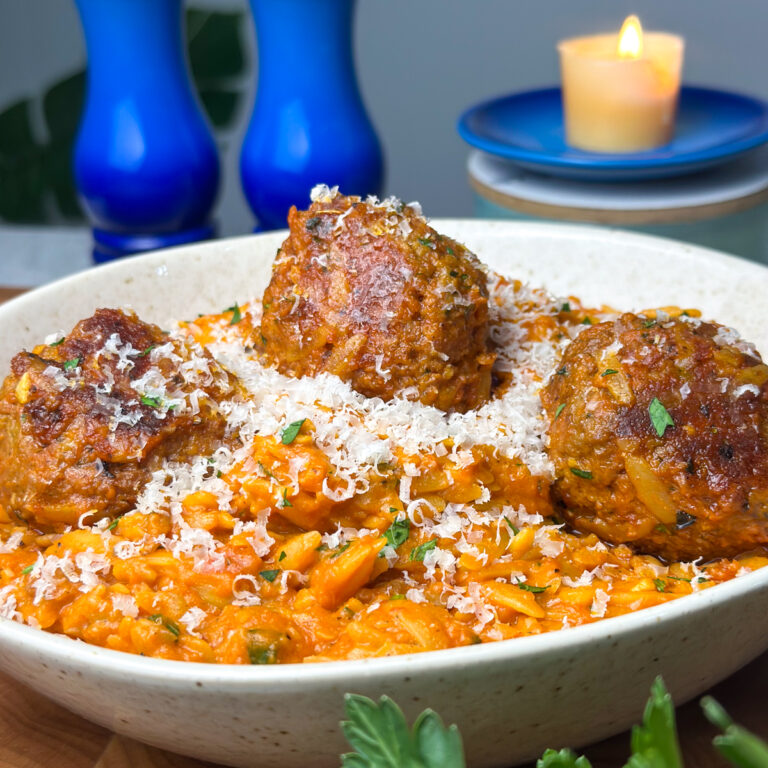 Garlic Meatball Orzo in a white bowl topped with grated parmesan and parsley